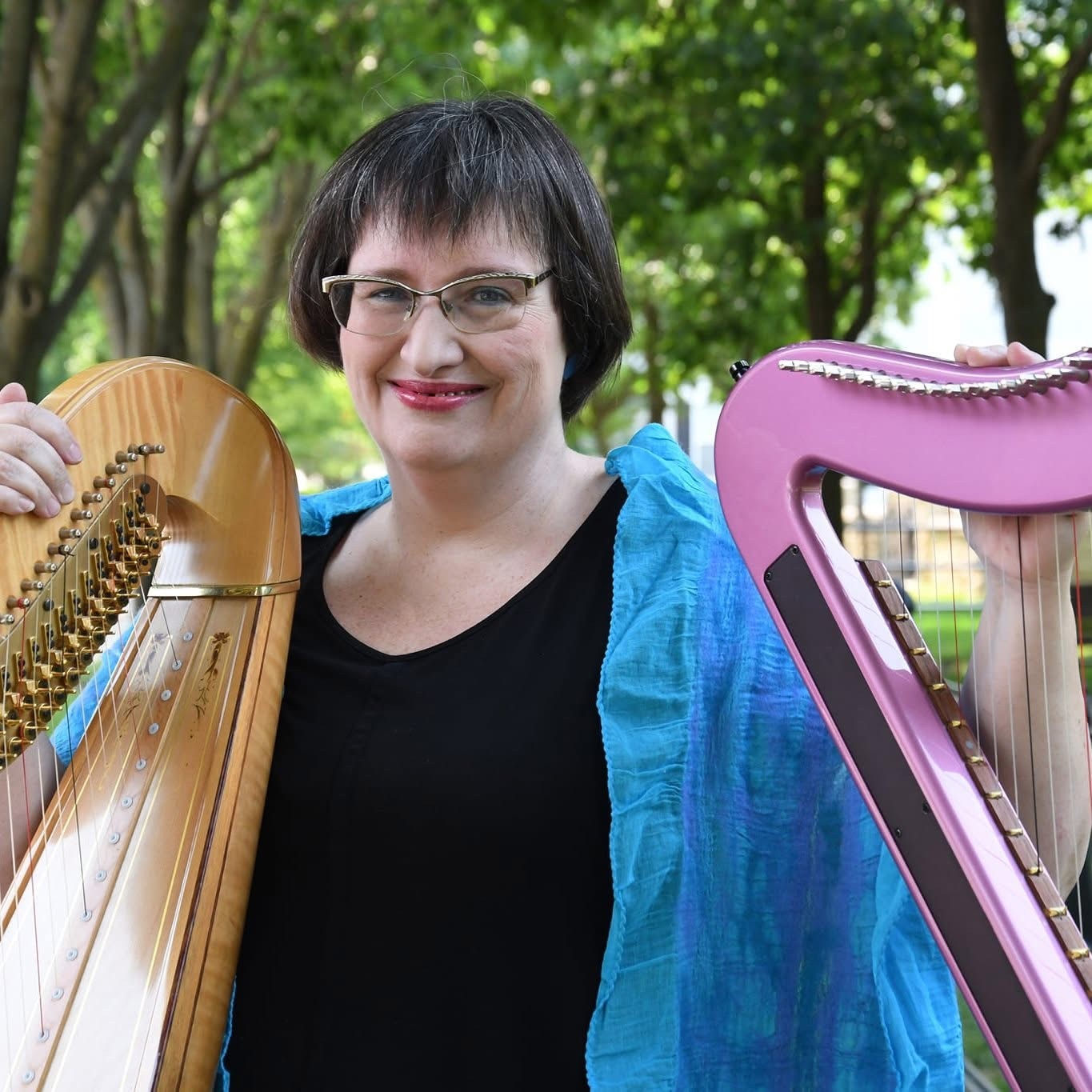 Photo of woman smiling with two harps on each side of her.