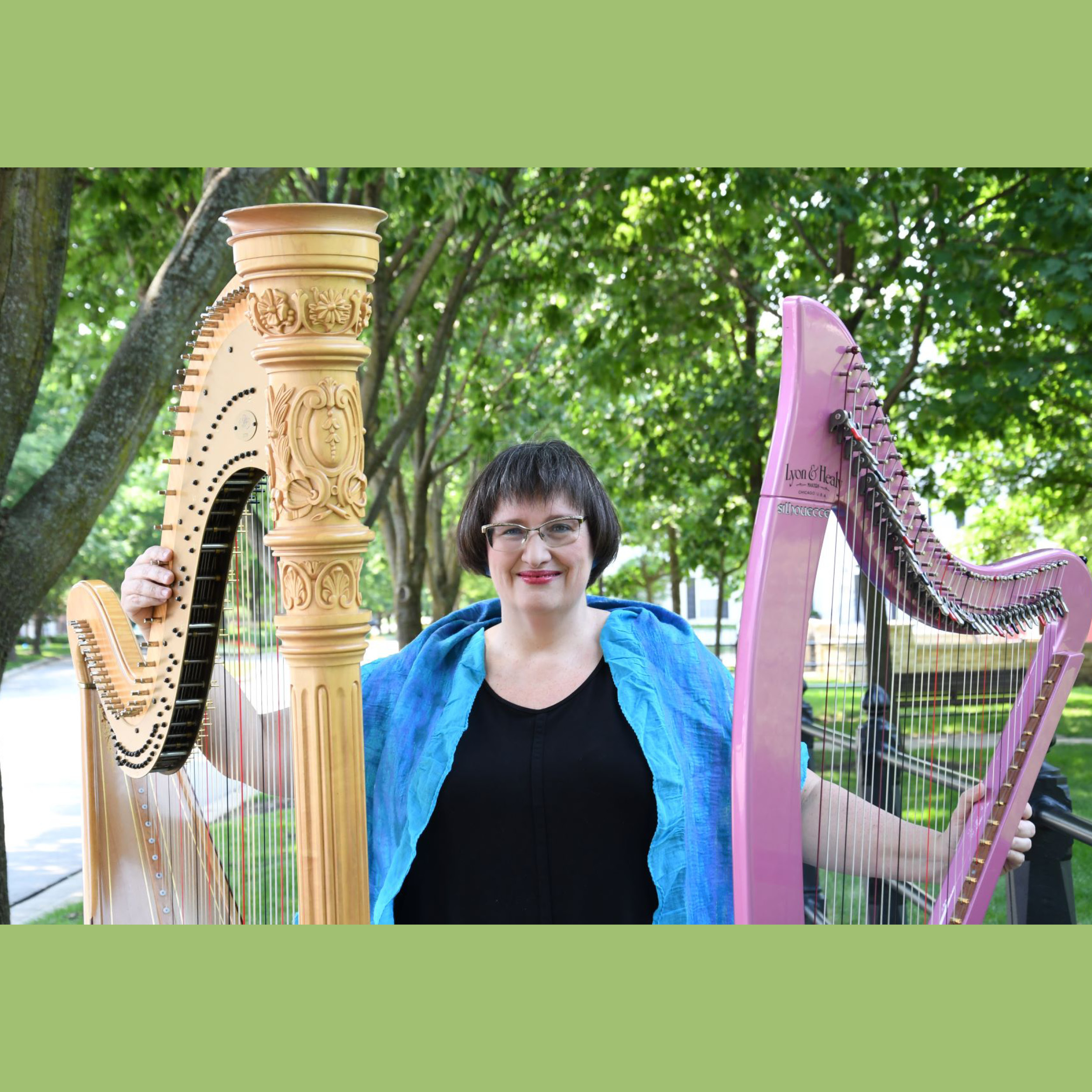 Woman standing outside with two harps