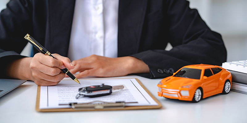 person signing title papers with car keys