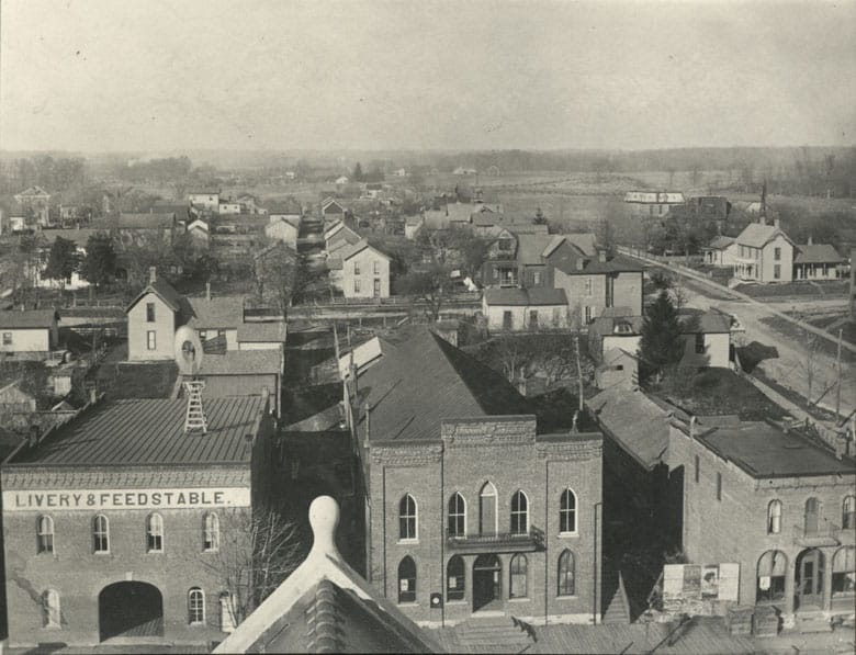 Jefferson Street north view from Courthouse tower, circa 1900. Visible is the former Opera House, where plays were performed and Albion High School basketball games were played on the second floor. See the billboard near the Opera House steps advertising the next play. Lutheran Church steeple is visible on the right. Note the windmill on the roof of the Livery and Feed Stable which provided water for the horses and the wooden sidewalk in front.