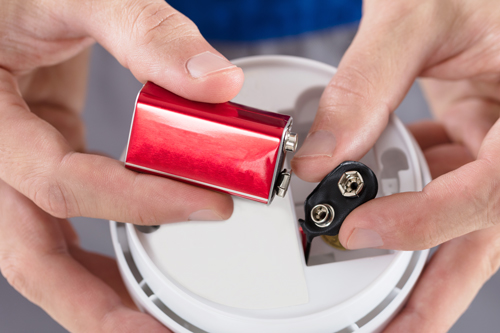 Hands connecting battery into smoke alarm