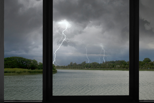 Storm with lightning strikes outside window