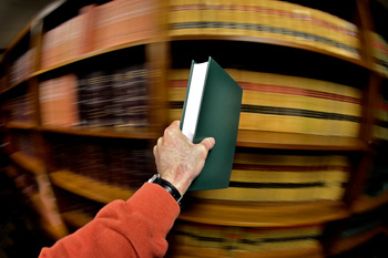 Person holding book by bookshelves