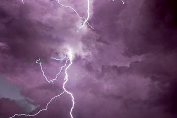 Lightning illuminates night sky with purple color