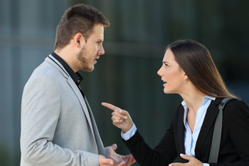 Angry woman pointing at male colleague
