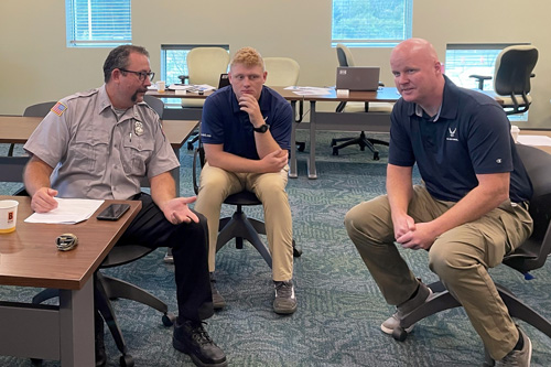 Three men discuss in small group