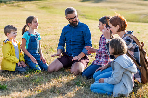 Man speaking to group of children on grass