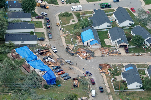 Houses damaged by tornado that have large blue tarps over roofs