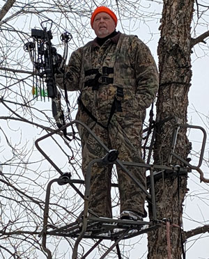 Man in tree stand with bow
