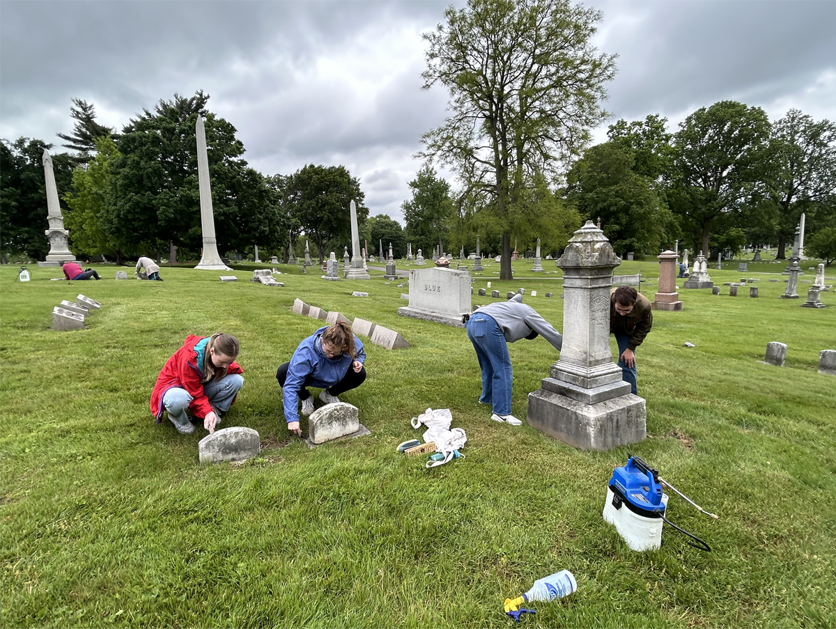 People cleaning tombstones in a cemetery.