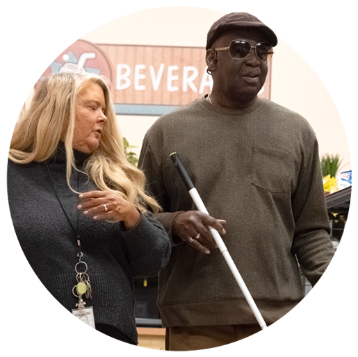 Blind man with white cane walking with woman.