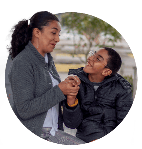 Woman talking to young boy in wheelchair.