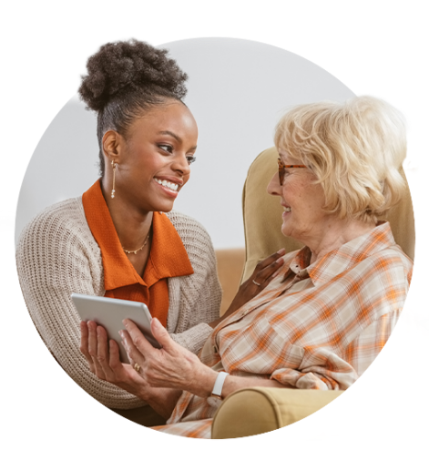 Young woman talking to older woman using tablet.