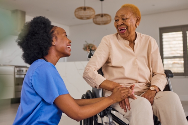Young female nurse talking to elderly woman in wheelchair.