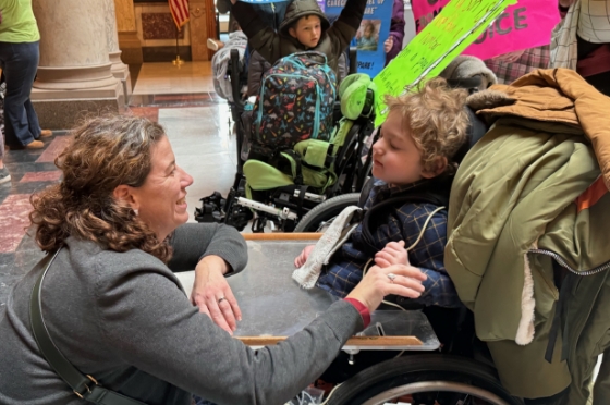 Woman talking to child in wheelchair.