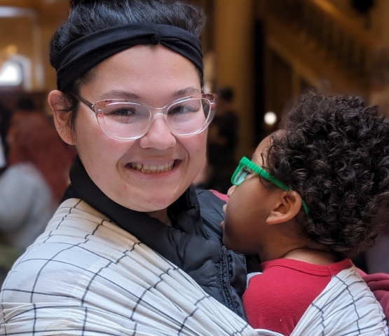 Woman holding child smiling at camera.