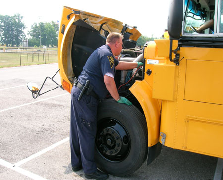 Master MCI Robert Burkhead inspects under the hood of a school bus.