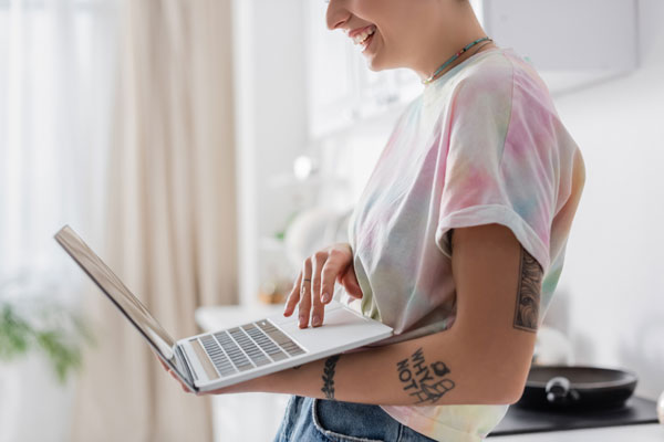 Tattooed woman using her laptop to add her endorsement to her license.