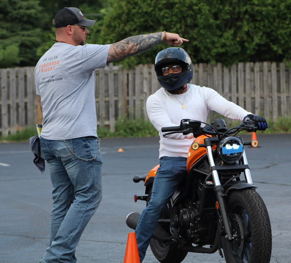 Motorcycle training instructor directing a course participant on his motorcycle.