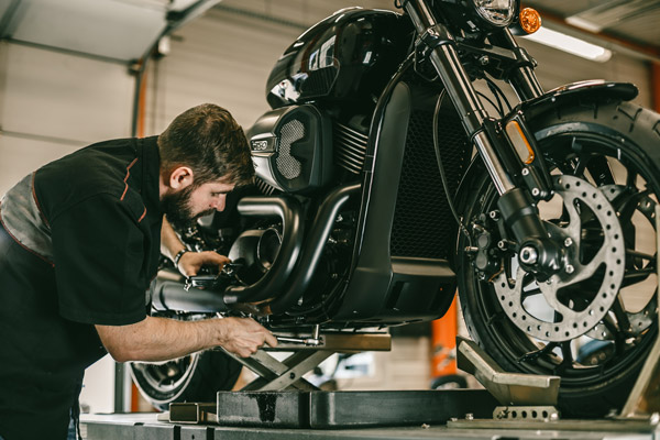 Man using a wrench to tight a bolt on the underside of his motorcycle.