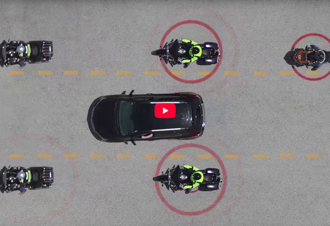 A group of motorcycle riders in a formation around a vehicle.